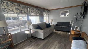 Ein Wohnzimmer mit einer Couch, einem Schlafsofa, einem runden Tisch und einer hölzernen Bank.