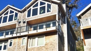 A multi-story building with a balcony on the second floor, a covered entrance with stairs, and a clear view of the surrounding area. - AMAZING OCEAN VIEW LUXURY Beach Home           !The Skyscraper!  Netarts (Netarts)