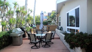 An outdoor patio with a grill, dining table, chairs, and a covered umbrella.