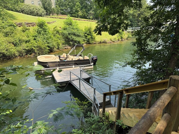 A boat docked at a wooden pier with a stone wall in the background.