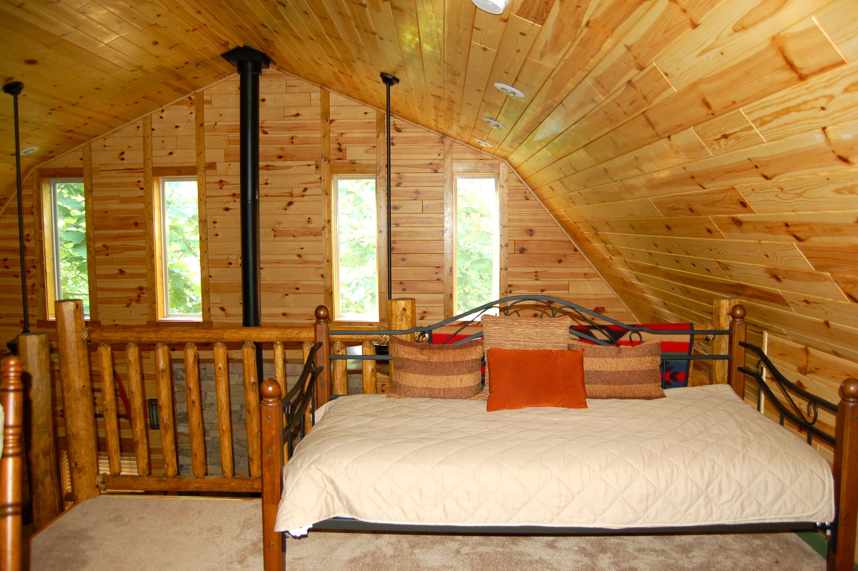 Ein Schlafzimmer einer Holzhütte mit einem Bett, einem Holz-Kopfteil und einem Fenster.