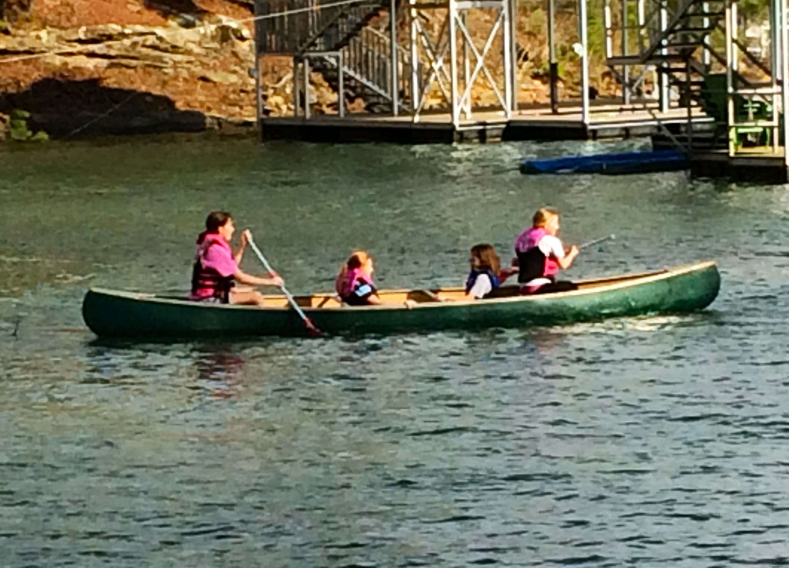 A canoe with four people on a calm body of water.