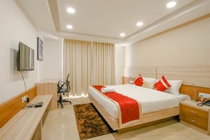 A modern hotel room with a large bed, bedside tables, a desk, and a television. - Siesta Medanta Medicity (Gurugram)
