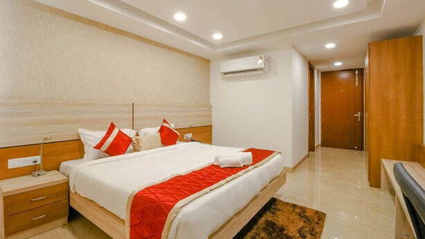 Una habitación de hotel moderna con una cama grande, una mesita de noche, un armario de madera y un equipo de aire acondicionado.