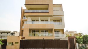 Un edificio residencial de varios pisos con balcones, ventanas amplias y una entrada con portón.