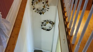 Una escalera con peldaños alfombrados, barandas blancas y dos adornos en la pared.