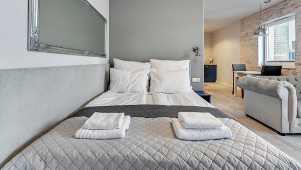 Ett modernt hotellrum med en stor säng, en soffa, ett skrivbord och en stor spegel.