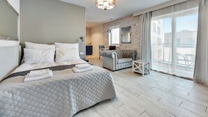 Ett modernt hotellrum med en stor säng, en soffa, ett litet bord och en balkong med utsikt.