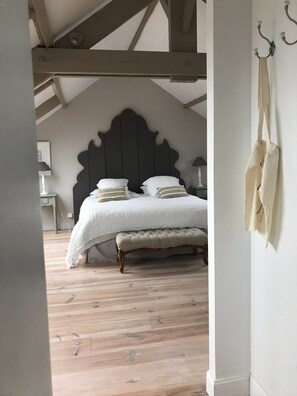 A bedroom with a dark headboard, a white bedspread, and a bench.