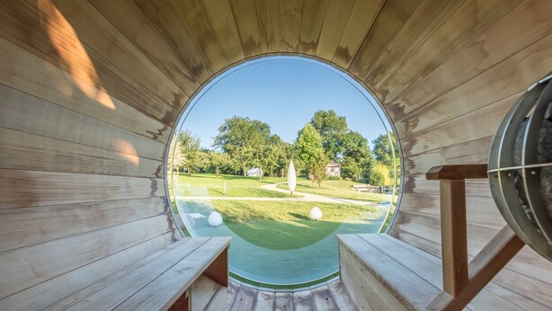 Une structure circulaire en bois, dotée de bancs et offrant une vue sur un terrain de golf.