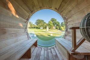 Een ronde houten constructie met banken en uitzicht op een golfbaan.