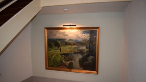 A framed landscape painting on a wall in a hallway. - Messewohnung Augusta (Wuppertal)