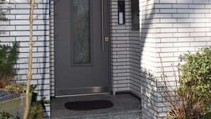 A modern building entrance with a gray door, a small porch, and a mailbox. - Messewohnung Augusta (Wuppertal)