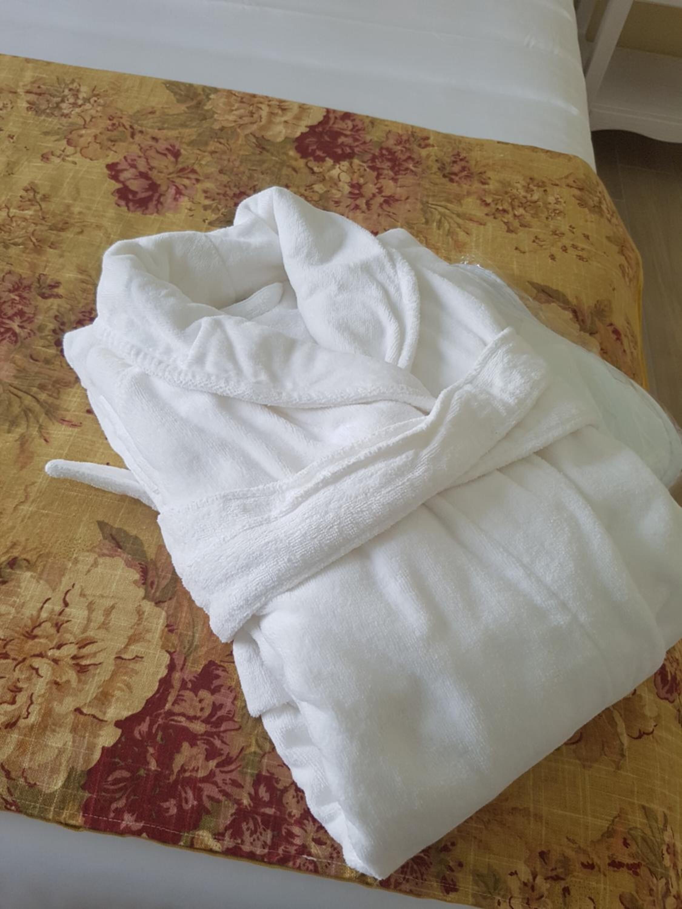 Un albornoz blanco sobre una cama con una colcha de estampado floral.