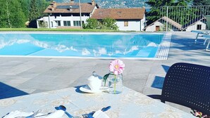 A poolside dining area with a table set for two, overlooking a mountainous landscape.
