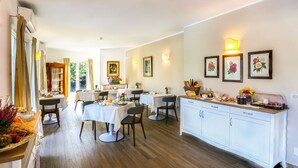 A dining area with multiple tables, chairs, and a kitchen counter with food items.