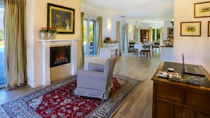 A spacious living room with a fireplace, a dining area, and a kitchen in the background.