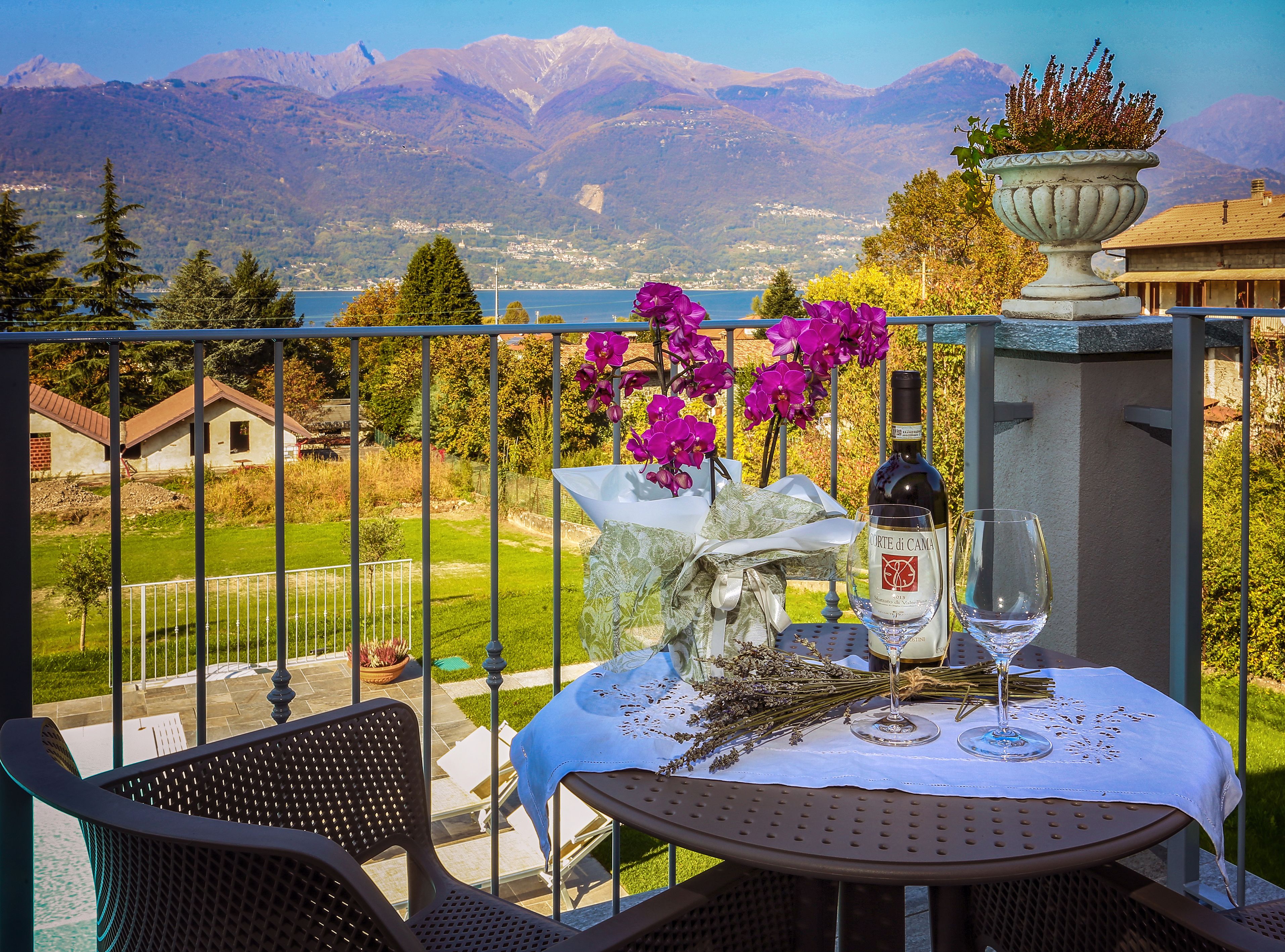 Un balcon avec une table dressée pour deux personnes, offrant une vue sur un paysage montagneux.