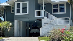 A two-story house with a covered garage, a front porch, and a staircase leading to the second floor. - Sea Salt Cottage - Beach front neighborhood, next to downtown restaurants (Isle of Palms)