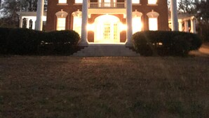 A large, two-story building with a central entrance flanked by columns, a balcony on the upper floor, and a symmetrical facade. - Beautiful Farmhouse near Tuscaloosa (Fayette)
