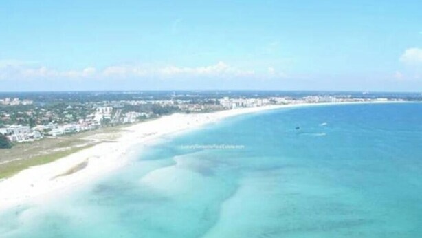 Vista aérea de una zona costera con playa de arena y mar azul cristalino.