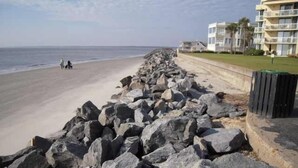 A beach with a rocky breakwater and a row of buildings with balconies. - Stylish Townhome by K&P Hotel - LABOR DAY SPECIAL, 5 for 4; 4 for 3.5 (St. Simons Island)