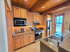 A kitchen with wooden cabinets, a stainless steel sink, a stove, and a refrigerator.