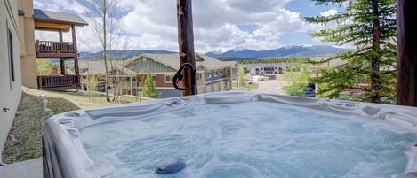 Un jacuzzi con vistas a una zona residencial y montañas al fondo.