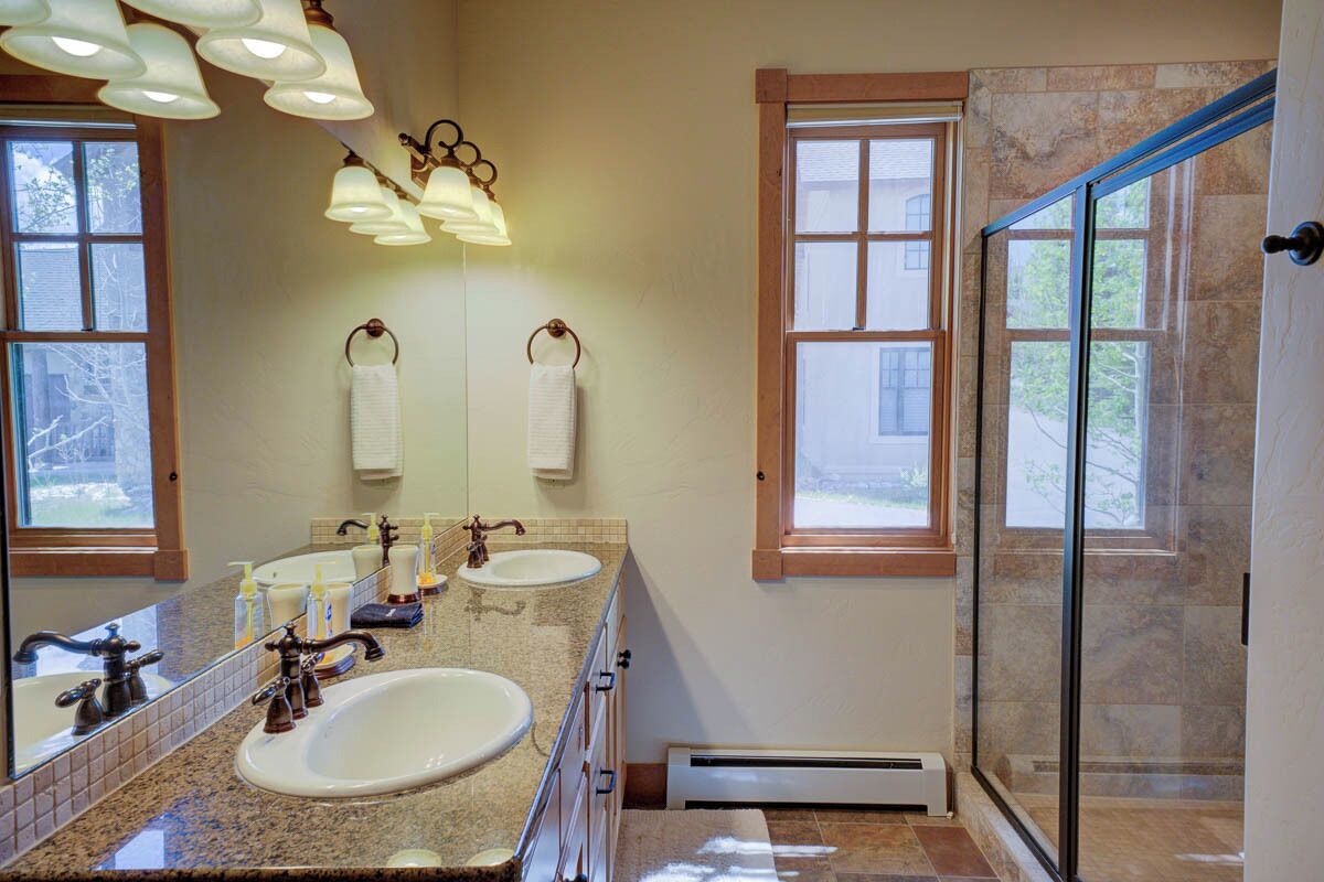 Ein Badezimmer mit zwei Waschbecken, einem großen Spiegel und einer Duschkabine aus Glas.
