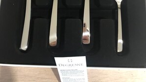 Un juego de cubiertos de acero inoxidable en una caja negra con la etiqueta que dice “DEGRENE PARIS”.