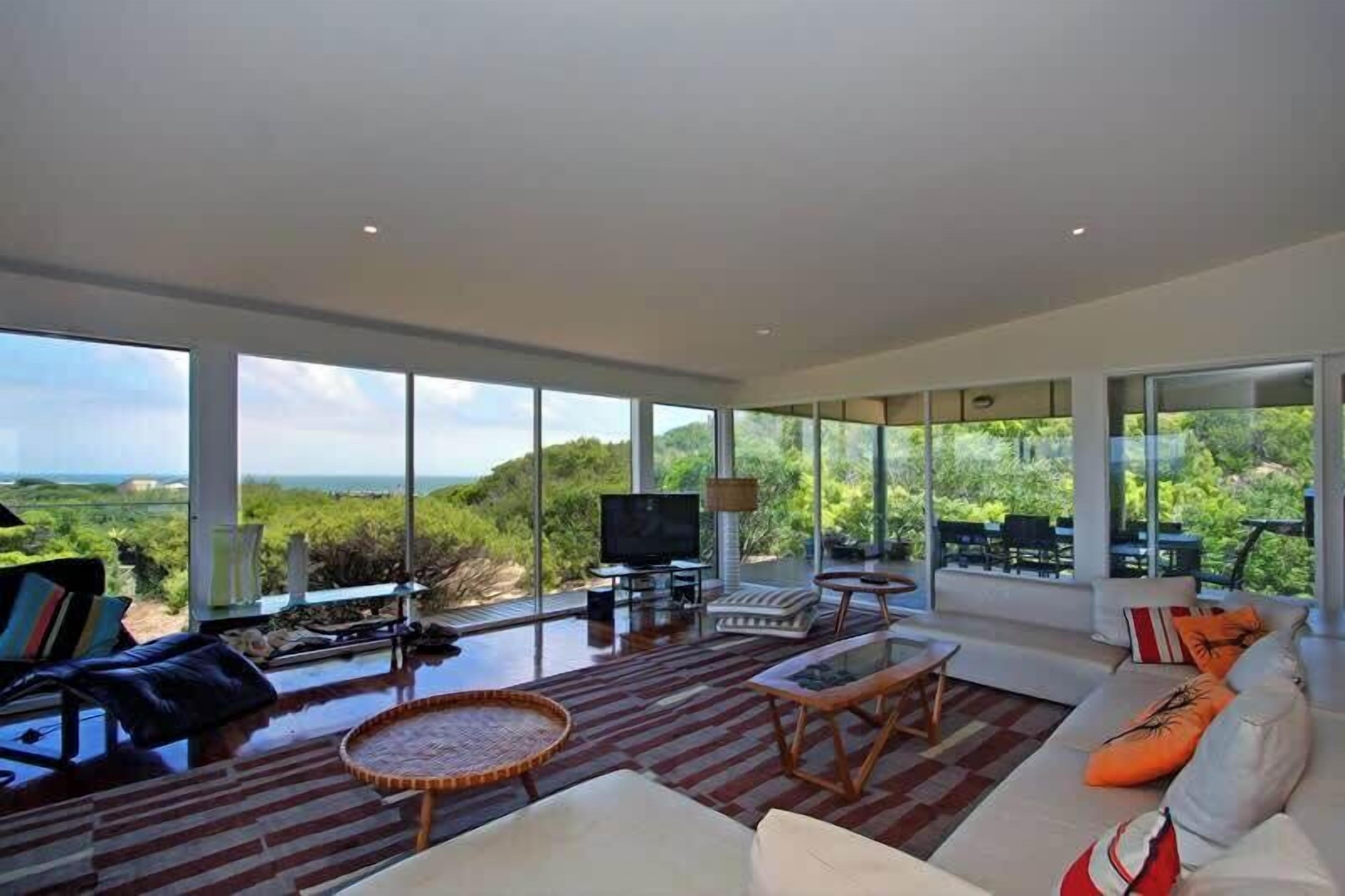 A spacious living room with a large TV, comfortable seating, and a view of the outdoors.