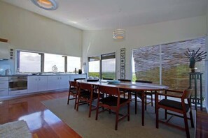 A modern kitchen with a dining area, large windows, and a view of the outdoors. - Dunes Retreat - amazing views of the ocean beach (St Andrews Beach)