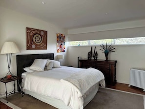 A bedroom with a large bed, a nightstand, a dresser, and a window with a view. - Dunes Retreat - amazing views of the ocean beach (St Andrews Beach)
