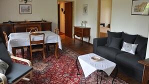 Una sala de estar acogedora con un sofá, sillas, una mesa de comedor y una araña.