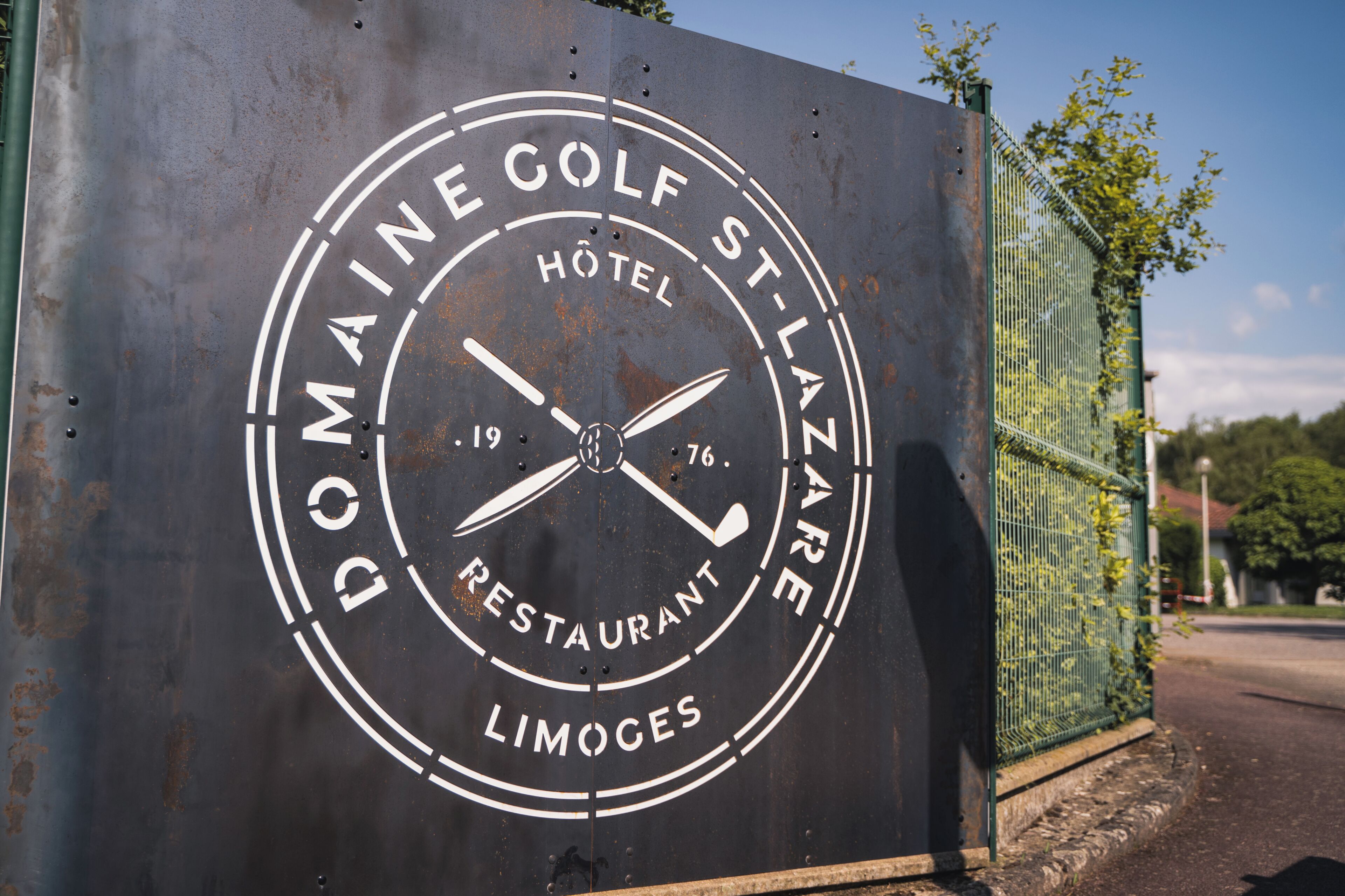 A circular sign with the text 'Domaine Golf St-Lazare Hotel Restaurant Limoges.'