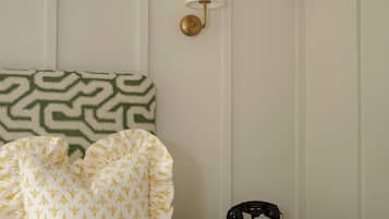 A neatly made bed with patterned pillows, a bedside lamp, a telephone, and a small wooden nightstand.