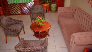 A reception area with patterned chairs, a sofa, and a table with a floral arrangement. - Greenvale Hotel (Ruiru)