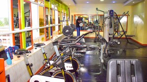 A gym with exercise equipment, mirrors, and a window with a view of the outside. - Greenvale Hotel (Ruiru)