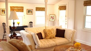 A living room with a beige sofa, a round coffee table with a tray, and a lamp. - Luxury Country Cottage with Spectacular Blue Ridge Mountain Views! (Stanardsville)