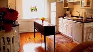 A kitchen with white cabinets, a wooden table, and a window with flowers. - Luxury Country Cottage with Spectacular Blue Ridge Mountain Views! (Stanardsville)
