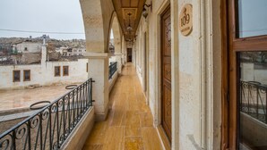 A corridor with a tiled floor, wooden doors, and a balcony with a metal railing. - Lucky Cave Cappadocia (Nevsehir)