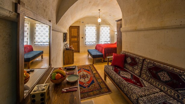 A cozy room with a wooden bench, a sofa, and a dining table with fruits and utensils. - Lucky Cave Cappadocia (Nevsehir)
