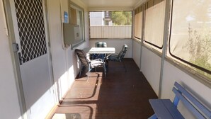A narrow corridor with a table and chairs, a bench, and a window with a view of buildings.