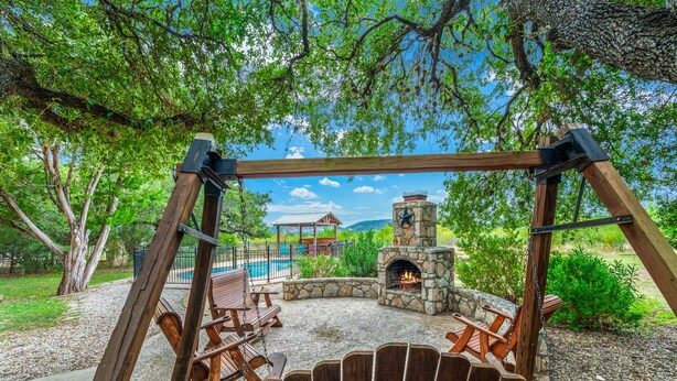 Un espacio al aire libre con una chimenea de piedra y sillas mecedoras de madera.