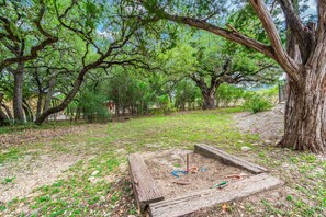 Surrounded by mature trees, this serene outdoor space features a fire pit and rustic wooden structure.
