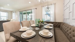 A dining area with a wooden table set for four, surrounded by beige chairs. - Colorful Bright Home with Fun Loft in Encore (Kissimmee)