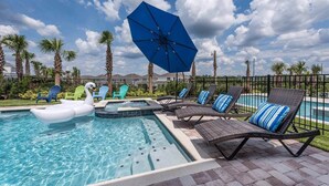 A swimming pool with lounge chairs, a hot tub, and a swan float. - Colorful Bright Home with Fun Loft in Encore (Kissimmee)