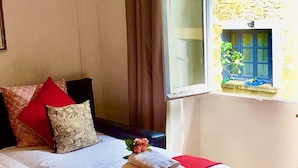 Un dormitorio con una cama grande, una ventana que da a un muro de piedra y suelo de madera.