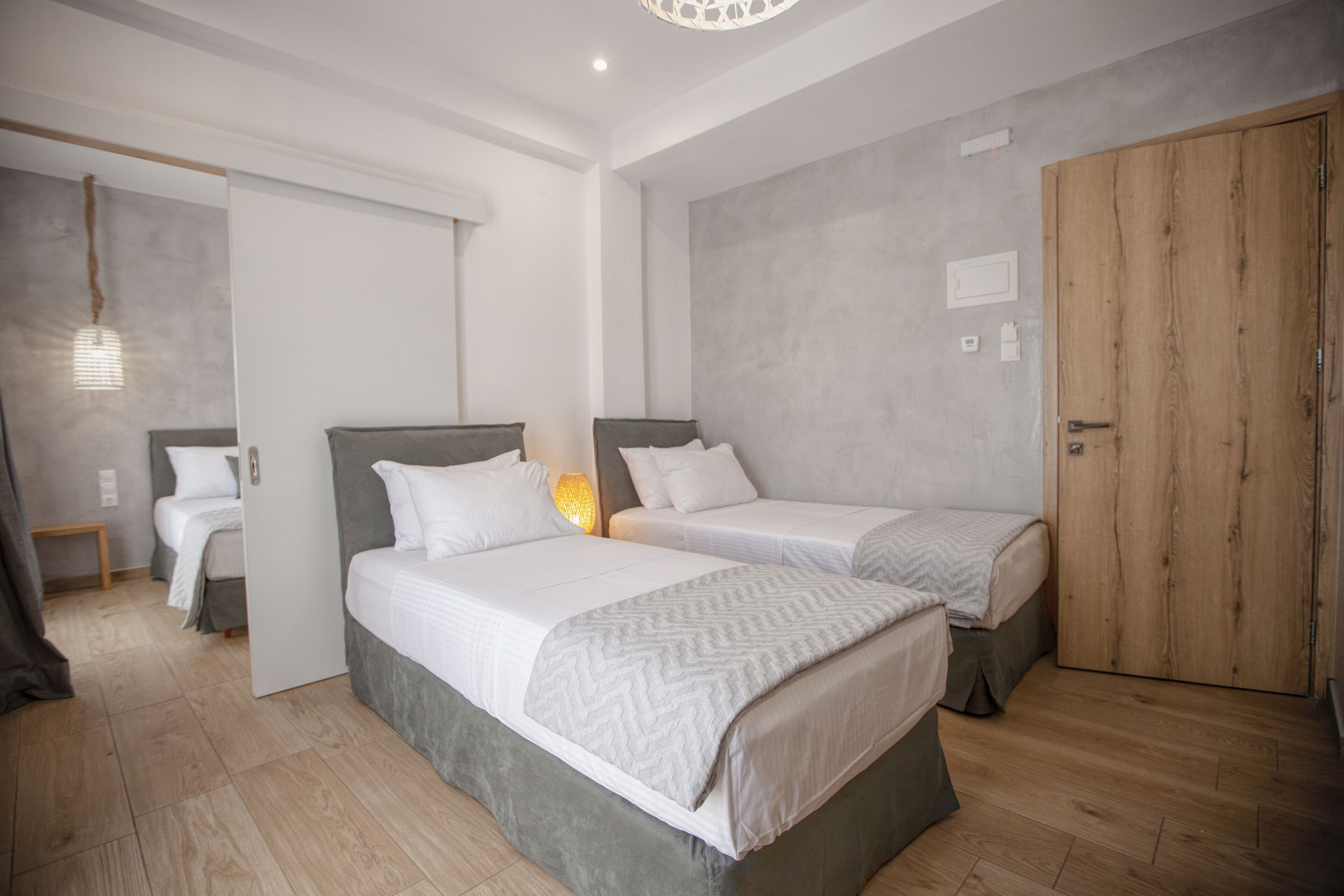 A modern bedroom with two single beds, a wooden wardrobe, and a small bedside table.