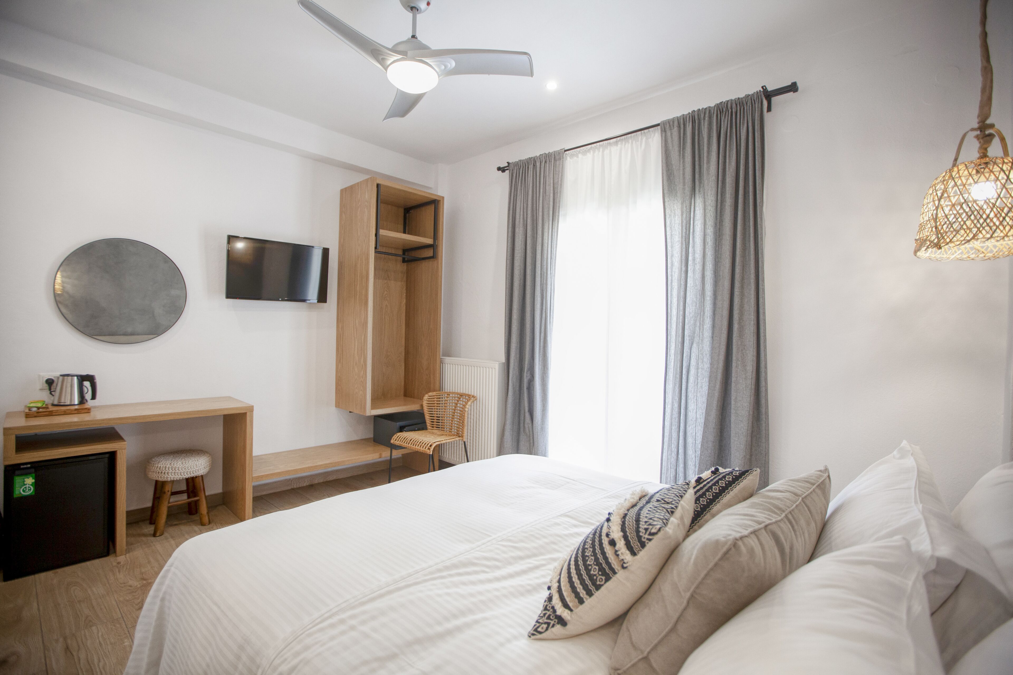 Una habitación de hotel con cama, escritorio, silla, televisor y ventilador de techo.